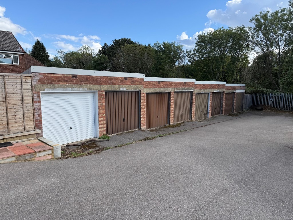 Lot: 173 - GARAGE BLOCK WITH CONSENT FOR CONSTRUCTION OF TWO HOUSES - Block of eight garages looking down the hill